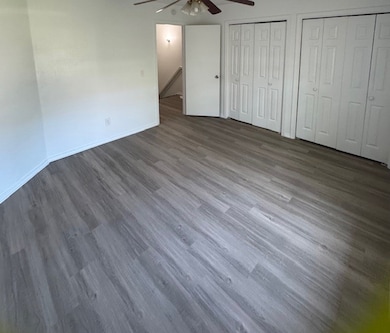 Unfurnished bedroom featuring two closets, wood finished floors, and ceiling fan