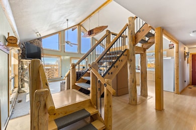Stairs with healthy amount of natural light, wood finished floors, a ceiling fan, and high vaulted ceiling