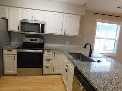 Kitchen featuring appliances with stainless steel finishes, light stone counters, decorative backsplash, and white cabinetry