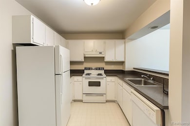 Kitchen with white appliances, dark countertops, and white cabinetry