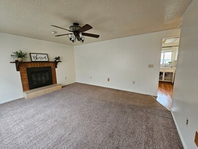 Unfurnished living room with carpet floors, a textured ceiling, a fireplace, and a ceiling fan