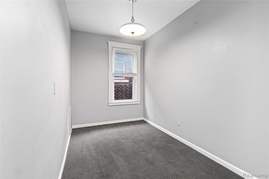 Unfurnished room featuring dark carpet and baseboards