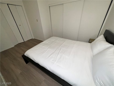 Bedroom with dark wood finished floors and baseboards
