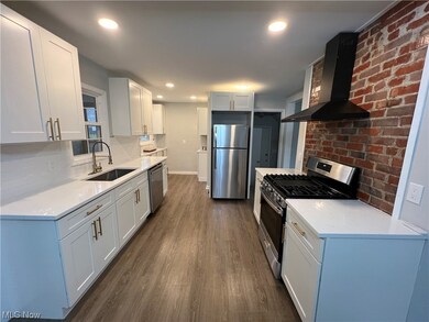 Kitchen featuring sink, wall chimney range hood, stainless steel appliances, dark wood-type flooring, and backsplash