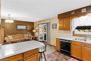 Kitchen with black dishwasher, light countertops, brown cabinets, a chandelier, and open floor plan