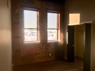 Unfurnished bedroom with a closet, brick wall, dar