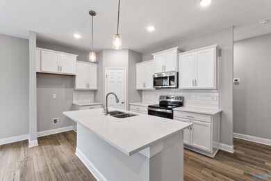 Spacious kitchen featuring quartz counter tops, backsplash, and pendant lighting.