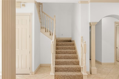 Stairway featuring ornate columns, tile patterned floors, and arched walkways