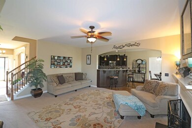Spacious Greatroom with gas fireplace, decorative mantle, plush carpeting, two oversized single windows with faux wood blinds, arched opening into the Kitchen/Breakfast Area, and opens to the Foyer.  