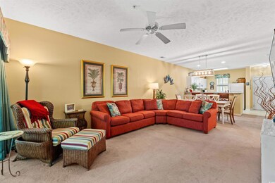 Living area featuring light carpet, a textured cei