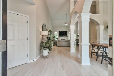 Foyer entrance featuring decorative columns, ceiling fan, high vaulted ceiling, wood finished floors, and arched walkways