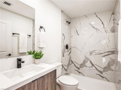 Bathroom featuring toilet, a marble finish shower,