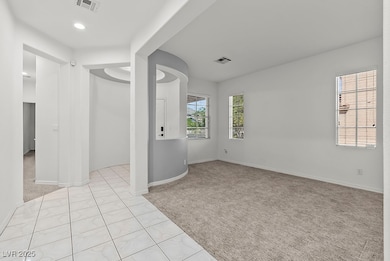 Living room with light colored carpet, entry, tile patterned flooring, and recessed lighting