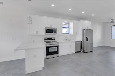 Kitchen featuring sink, white cabinetry, hanging l