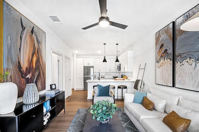 Living area featuring dark wood-type flooring and a ceiling fan