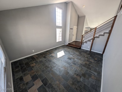 Foyer with baseboards, high vaulted ceiling, stone