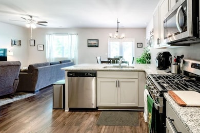 Kitchen featuring stainless steel appliances, open floor plan, a peninsula, dark wood-style flooring, and healthy amount of natural light