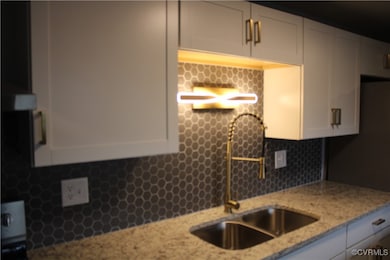 Kitchen featuring white cabinets, tasteful backspl