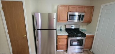 Kitchen appliances with stainless steel finishes, wood-type flooring, and brown cabinets