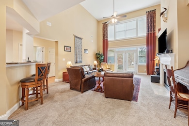 Opposite view of vaulted light-filled 2 story family room with open view to Chef's kitchen, gas fireplace, oversized windows, plus French doors leading to rear patio.