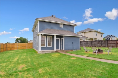 Back of house with an outdoor fire pit, a fenced backyard, a shingled roof, and entry steps