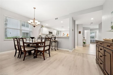 Dining area with a notable chandelier, a wealth of natural light, and light wood-type flooring