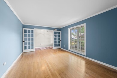 Relax in the living room with french doors, wood finished floors, and ornamental molding.