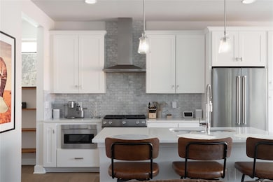 Kitchen featuring wall chimney range hood, applia