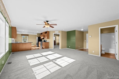 Unfurnished living room featuring light colored carpet and a ceiling fan