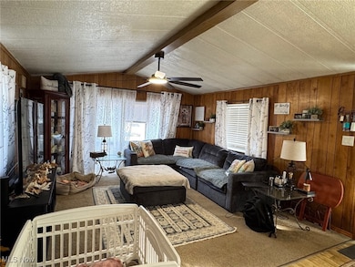 Living area with wooden walls, a ceiling fan, and wood finished floors