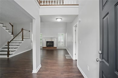 Foyer with wood finished floors, stairs, a textured ceiling, and a fireplace