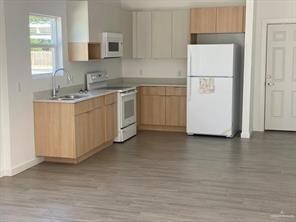 Kitchen with sink, light brown cabinets, white app