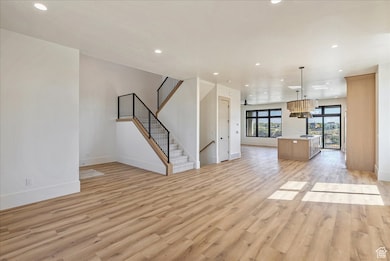 Unfurnished living room with recessed lighting, light wood-style flooring, and stairs