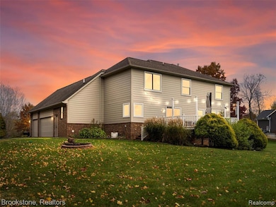 Back of property at dusk with brick siding and a yard