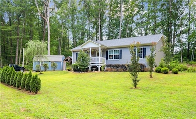 View of front facade with a porch, a front yard, and a storage unit