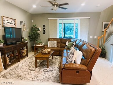 Tiled living room featuring stairs, a ceiling fan,