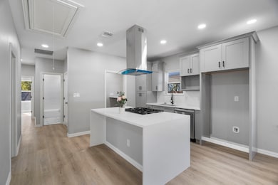 Kitchen featuring a kitchen island, light stone countertops, recessed lighting, light wood-style floors, and stainless steel dishwasher