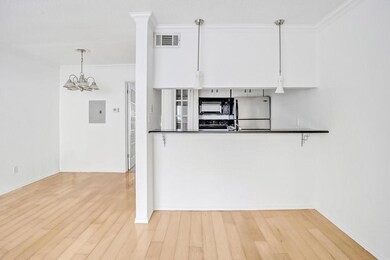 Kitchen with light hardwood / wood-style floors, white cabinetry, stainless steel fridge, ornamental molding, and an inviting chandelier
