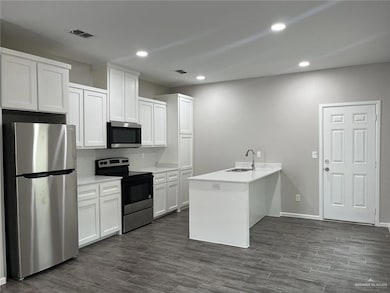 Kitchen featuring a peninsula, stainless steel appliances, recessed lighting, dark wood-type flooring, and white cabinetry