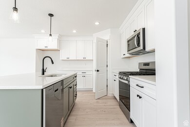 Kitchen with appliances with stainless steel finishes, recessed lighting, hanging light fixtures, white cabinetry, and light countertops