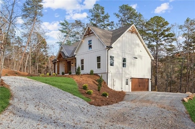 View of side of home featuring board and batten siding, driveway, a shingled roof, an attached garage, and a lawn