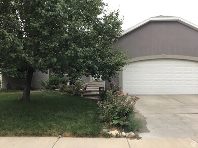 View of front of home with a front yard, driveway, an attached garage, and stucco siding