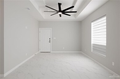 Unfurnished room featuring ceiling fan and a tray ceiling