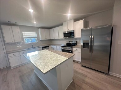 Kitchen featuring light wood-type flooring, a sink, white cabinets, and stainless steel appliances