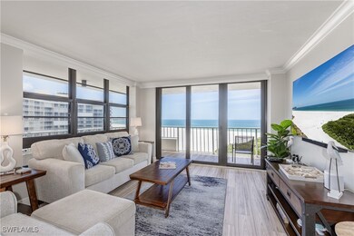 Living area featuring a water view, wood finished floors, a view of the beach, a wall of windows, and crown molding
