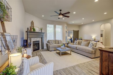 Living area featuring arched walkways, wood finished floors, recessed lighting, ceiling fan, and a fireplace