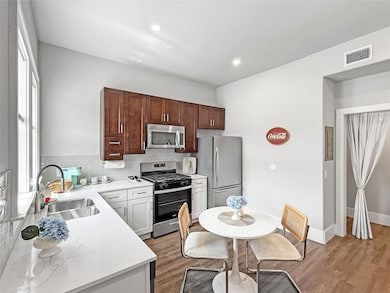 Kitchen with appliances with stainless steel finishes, tasteful backsplash, dark wood-style flooring, light stone counters, and recessed lighting