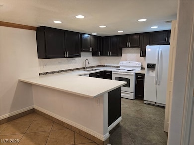 Kitchen featuring white appliances, a sink, dark c