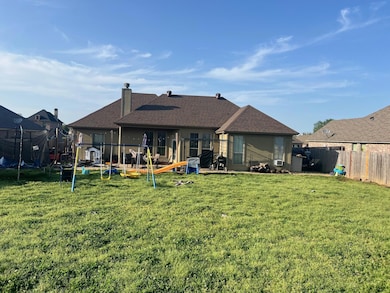 Back of house featuring a trampoline, a shingled r