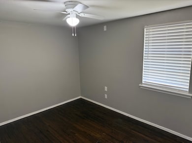 Unfurnished room featuring ceiling fan, baseboards, and dark wood-style flooring